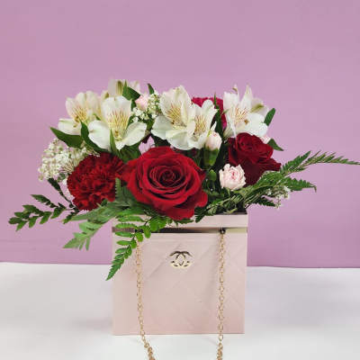 Red roses and white lilies in a pink gift box with a gold chain