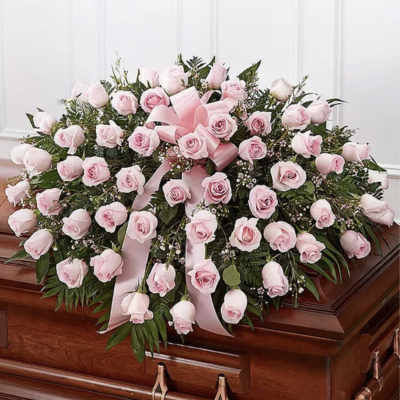 Pink rose casket spray with ribbon on a wooden coffin