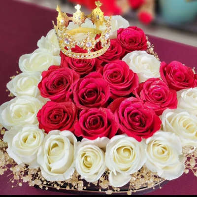 Red and white rose arrangement topped with a gold crown