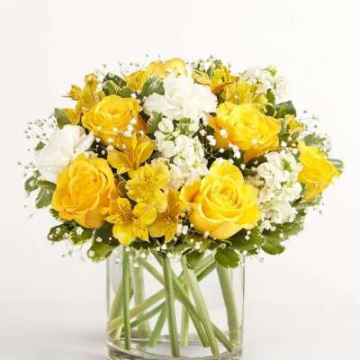 Yellow and white roses arranged in a clear glass vase