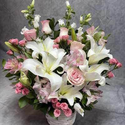 Pink roses and white lilies arranged in a white basket