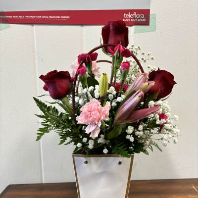 Mixed bouquet of red roses, pink carnations, and lilies in a white gift box