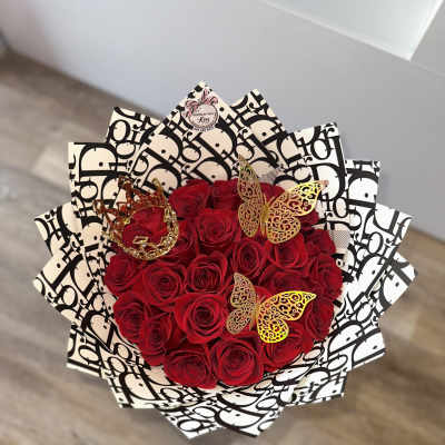 Bouquet of red roses wrapped in black-and-white patterned paper with butterfly accents