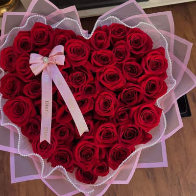 Heart-shaped bouquet of red roses with pink ribbon wrapping