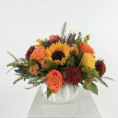 Orange and yellow mixed flower arrangement in a white vase