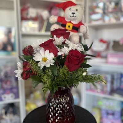 Red roses and white daisies in a red vase with a teddy bear topper
