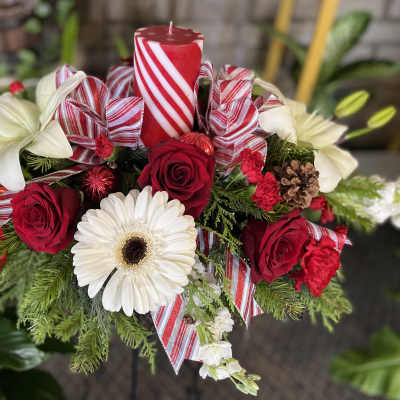 Red roses and white lilies arranged with a candle and striped ribbon