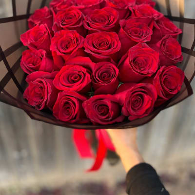 Bouquet of red roses wrapped in black paper with a red ribbon
