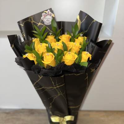 Bouquet of yellow roses wrapped in black paper with a gold ribbon