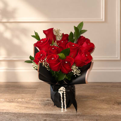Bouquet of red roses wrapped in black paper with pearl accents