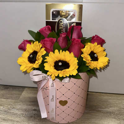 Pink roses and yellow sunflowers in a pink gift box with a ribbon