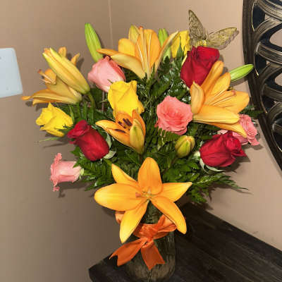 Bouquet of yellow lilies and red and pink roses in a glass vase
