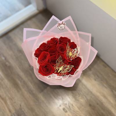 Bouquet of red roses wrapped in pink paper with butterfly decorations