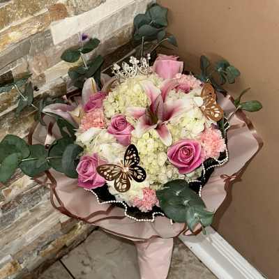 Pink roses and lilies arranged with hydrangeas and decorative butterflies