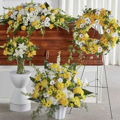 Yellow and white funeral floral arrangements around a casket