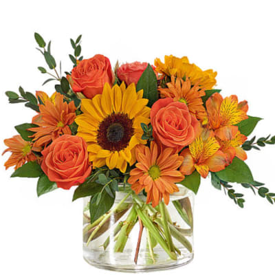 Orange roses and sunflowers in a clear glass vase