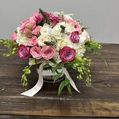 Pink and white rose bouquet in a glass vase with ribbon