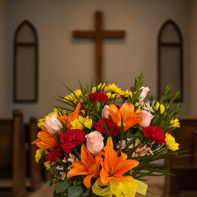 Colorful flower arrangement in a tall glass vase with a yellow ribbon