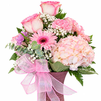Pink and white bouquet in a textured vase with a pink ribbon