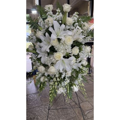 Large white floral standing arrangement with lilies and roses on an easel