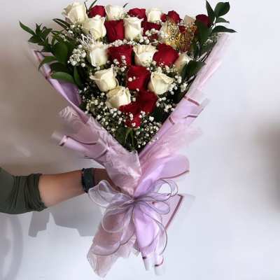 Bouquet of red and white roses wrapped in pink paper with a ribbon