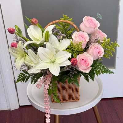 Basket arrangement of pink roses and white lilies