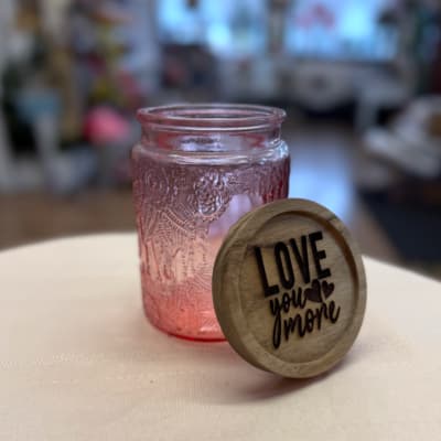 Pink glass jar with a wooden lid reading "Love you more"