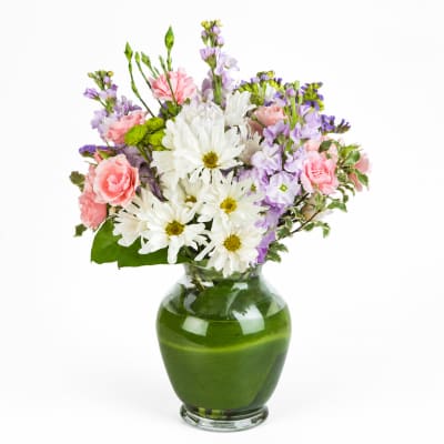 Bouquet of white daisies, pink carnations, and lavender flowers in a green glass vase
