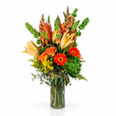 Tall bouquet of orange flowers and yellow lilies in a clear glass vase