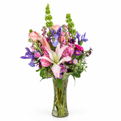 Mixed bouquet of pink, purple, and white flowers in a clear glass vase