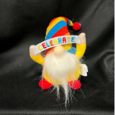 Small plush gnome with a rainbow hat and a "CELEBRATE" banner