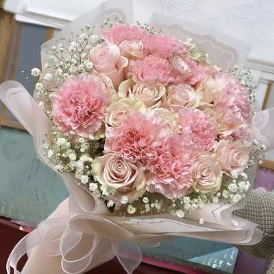 Pink roses and carnations in a pale wrapped bouquet