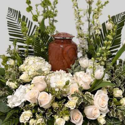 White roses and tulips arranged around a wooden urn