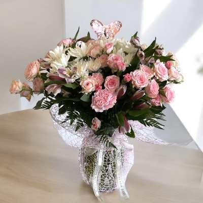 Pink roses and white daisies arranged in a wrapped vase bouquet
