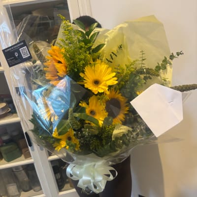 Bouquet of yellow sunflowers wrapped in clear plastic with a white ribbon