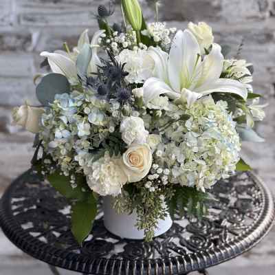 White lilies and hydrangeas arranged in a white vase