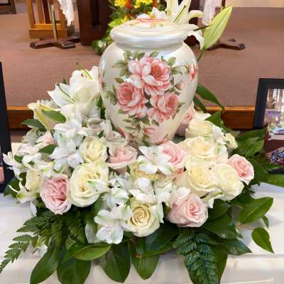 White urn surrounded by pink and white roses and lilies