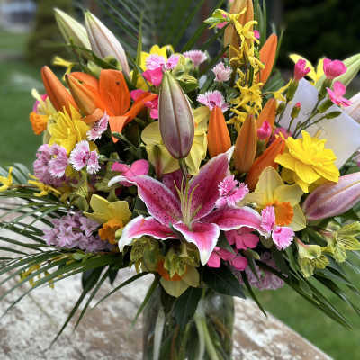 Colorful bouquet with lilies, daisies, and pink flowers in a glass vase