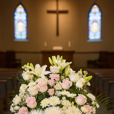 White and blush floral arrangement in a white vase with a ribbon
