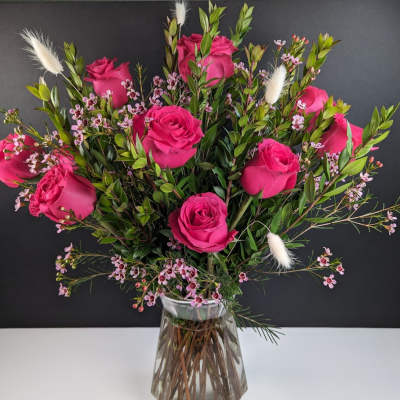Pink roses arranged in a clear glass vase with small filler flowers