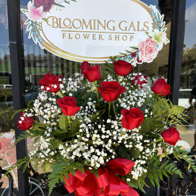 Red roses and baby's breath in a clear glass vase with a red ribbon