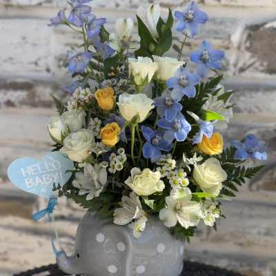 Blue and white flower arrangement in a gray elephant vase with a "Hello Baby" tag