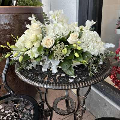 White floral arrangement with roses and hydrangeas in a low container