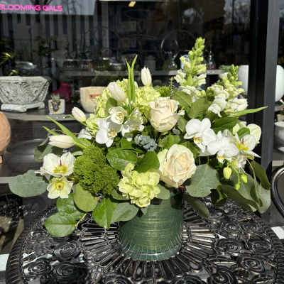 White and pale green floral arrangement in a green vase