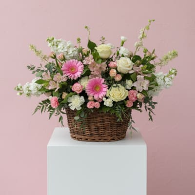 Basket arrangement of pink and white flowers with roses and daisies
