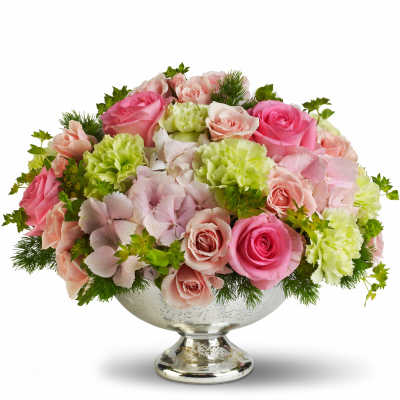 Pink and peach roses with green carnations in a silver pedestal bowl