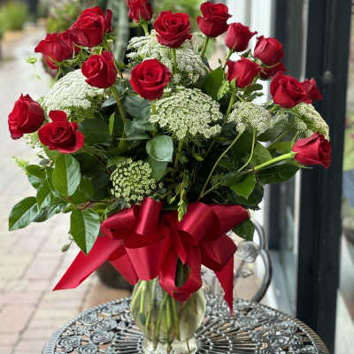Red roses in a clear glass vase with a red ribbon bow