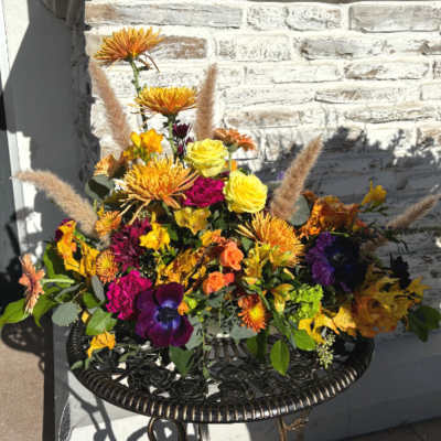 Colorful floral arrangement with yellow roses and orange blooms in a black metal table