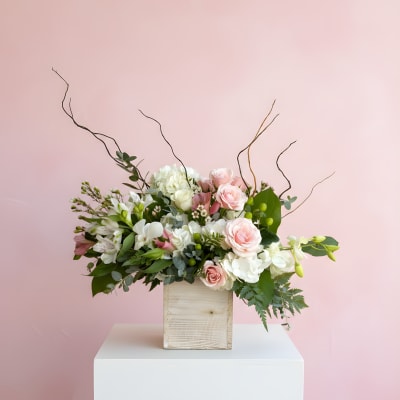 Pink and white floral arrangement in a wooden box