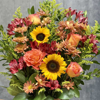 Basket arrangement with sunflowers, orange roses, and mixed blooms